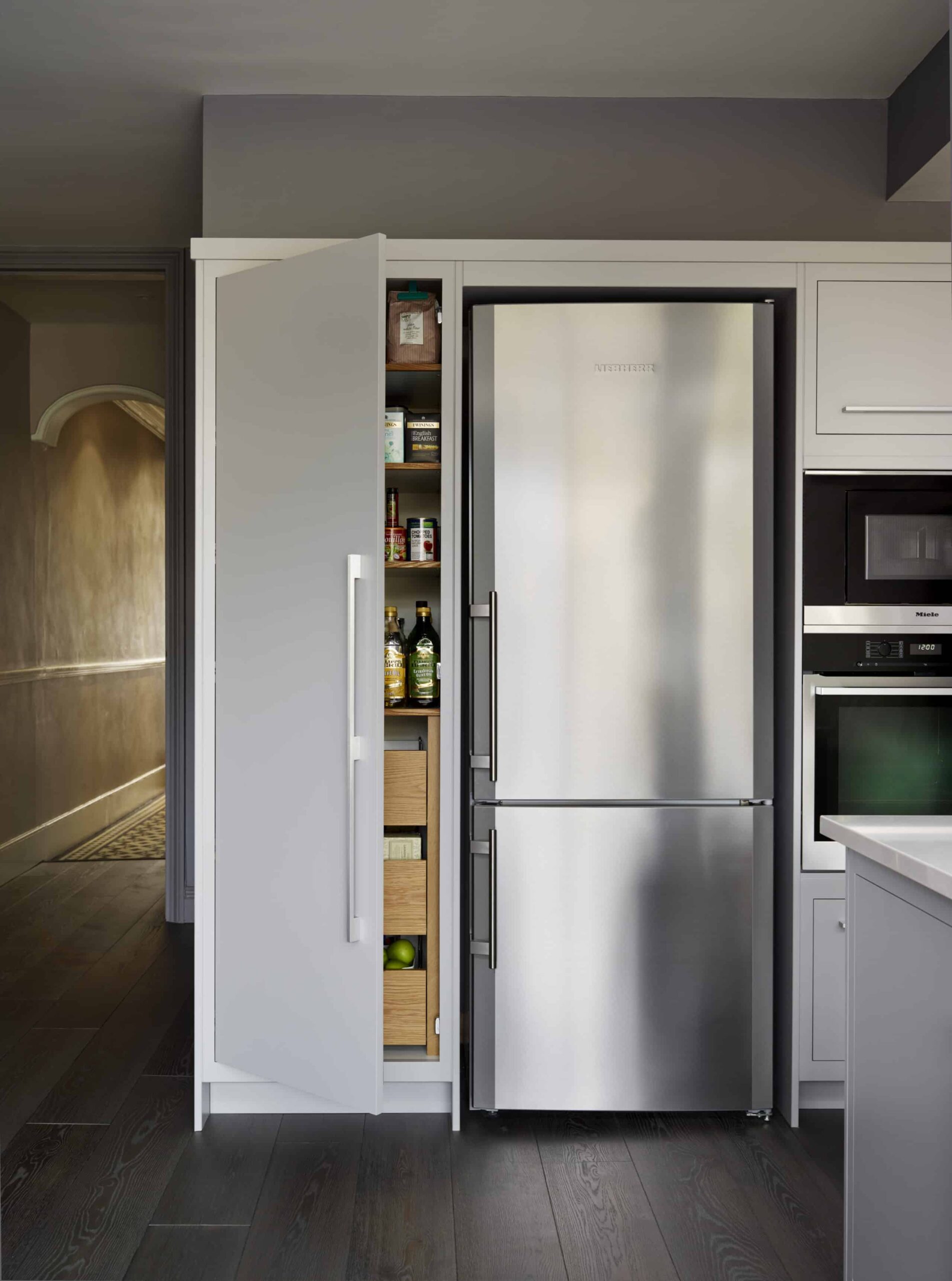 Open grey Linear pantry next to large refrigerator