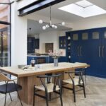 Open plan dining area overlooking navy industrial style Shaker kitchen