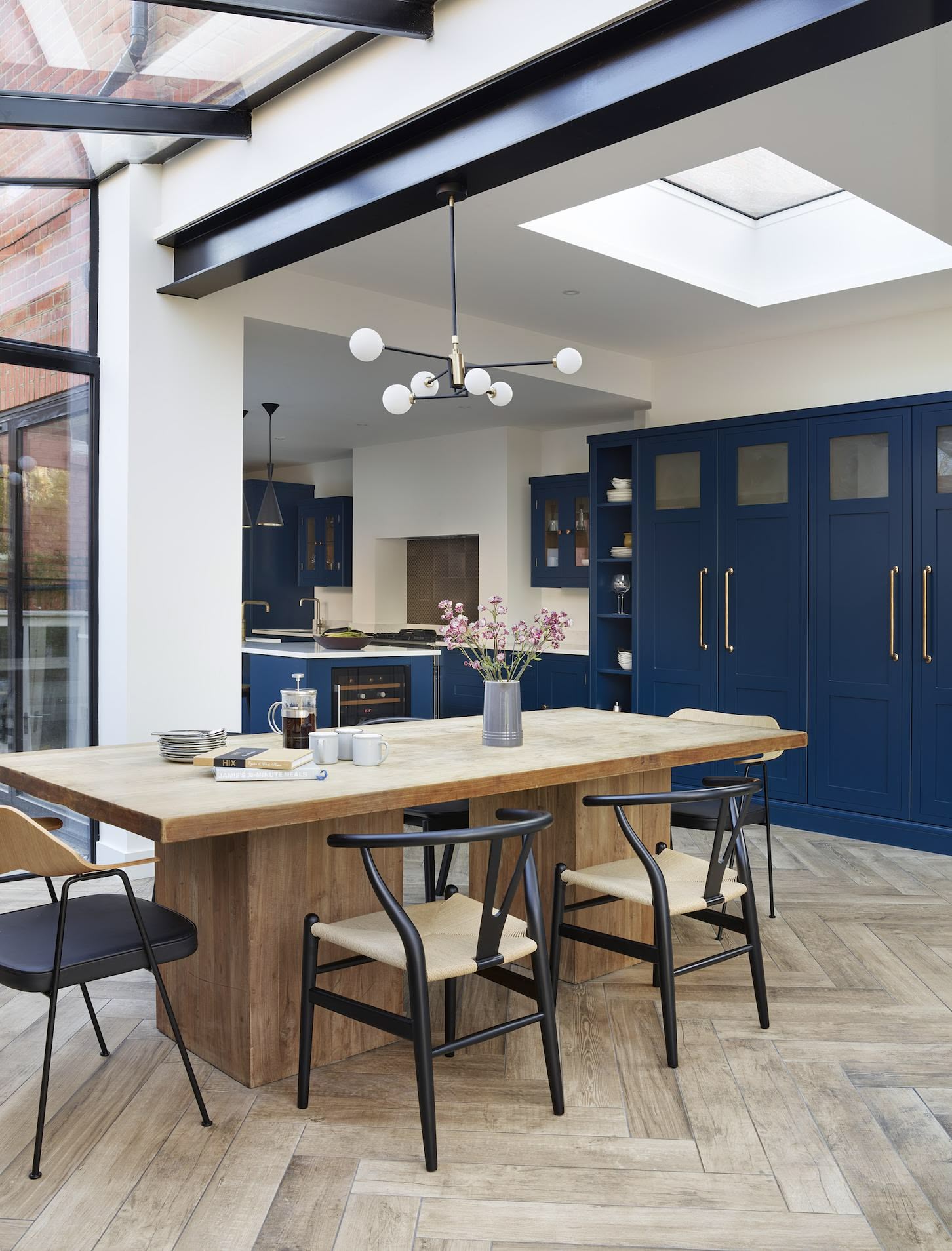 Open plan dining area overlooking navy industrial style Shaker kitchen
