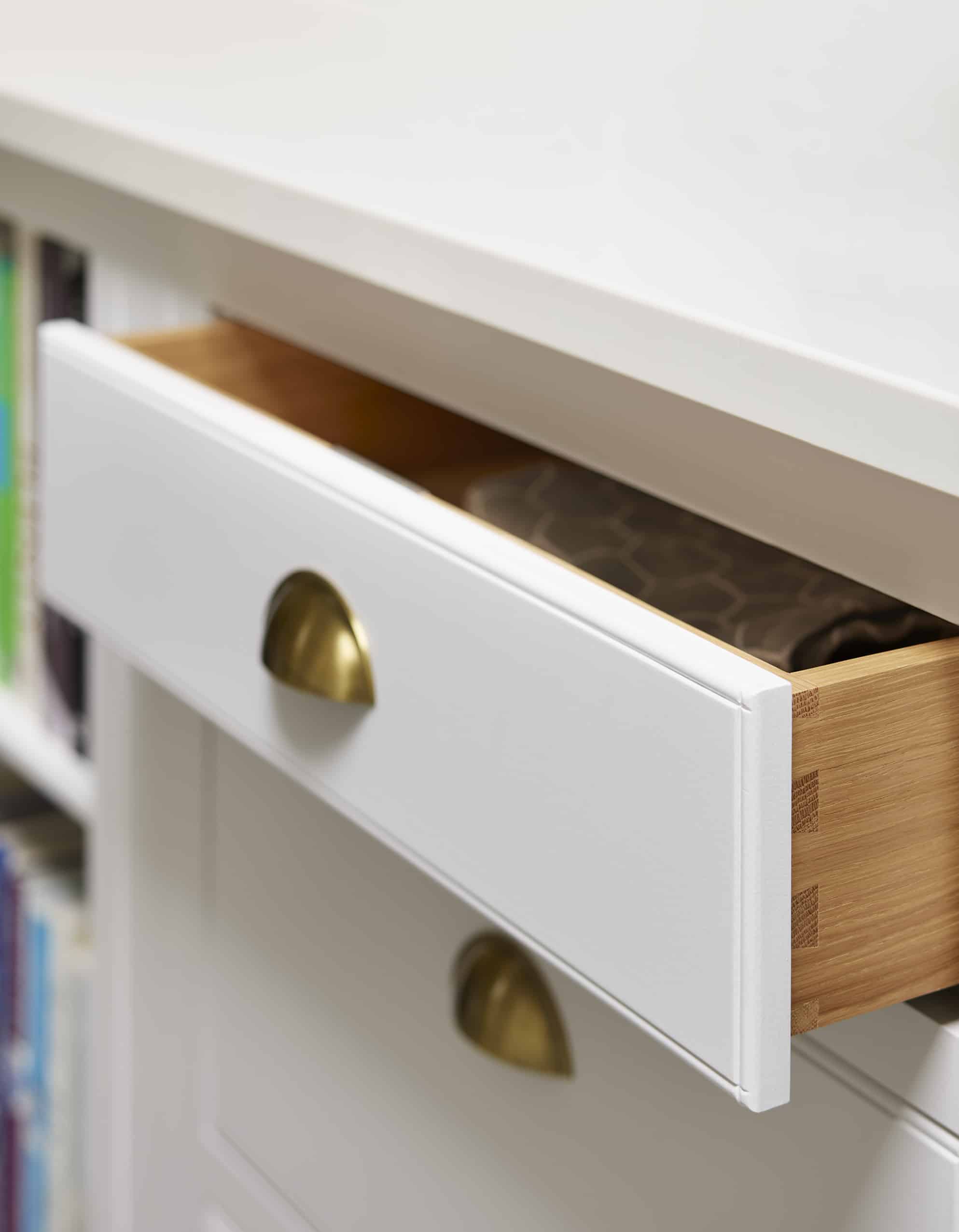 Close up of a white Arbor kitchen draw featuring a gold handle