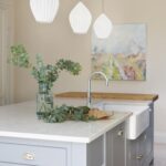 Grey kitchen island with white worktop featuring basin sink and silver tap