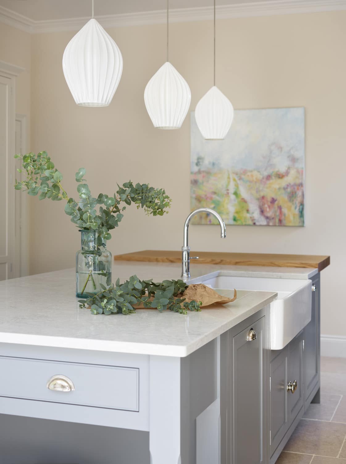 Grey kitchen island with white worktop featuring basin sink and silver tap