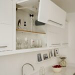 White Linear overhead kitchen cabinet open to reveal organised shelving