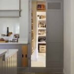 Tall grey pantry on the end of a kitchen worktop, open to show organised storage and drawers