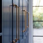 Closeup of navy Shaker kitchen cabinetry with industrial style brass handles