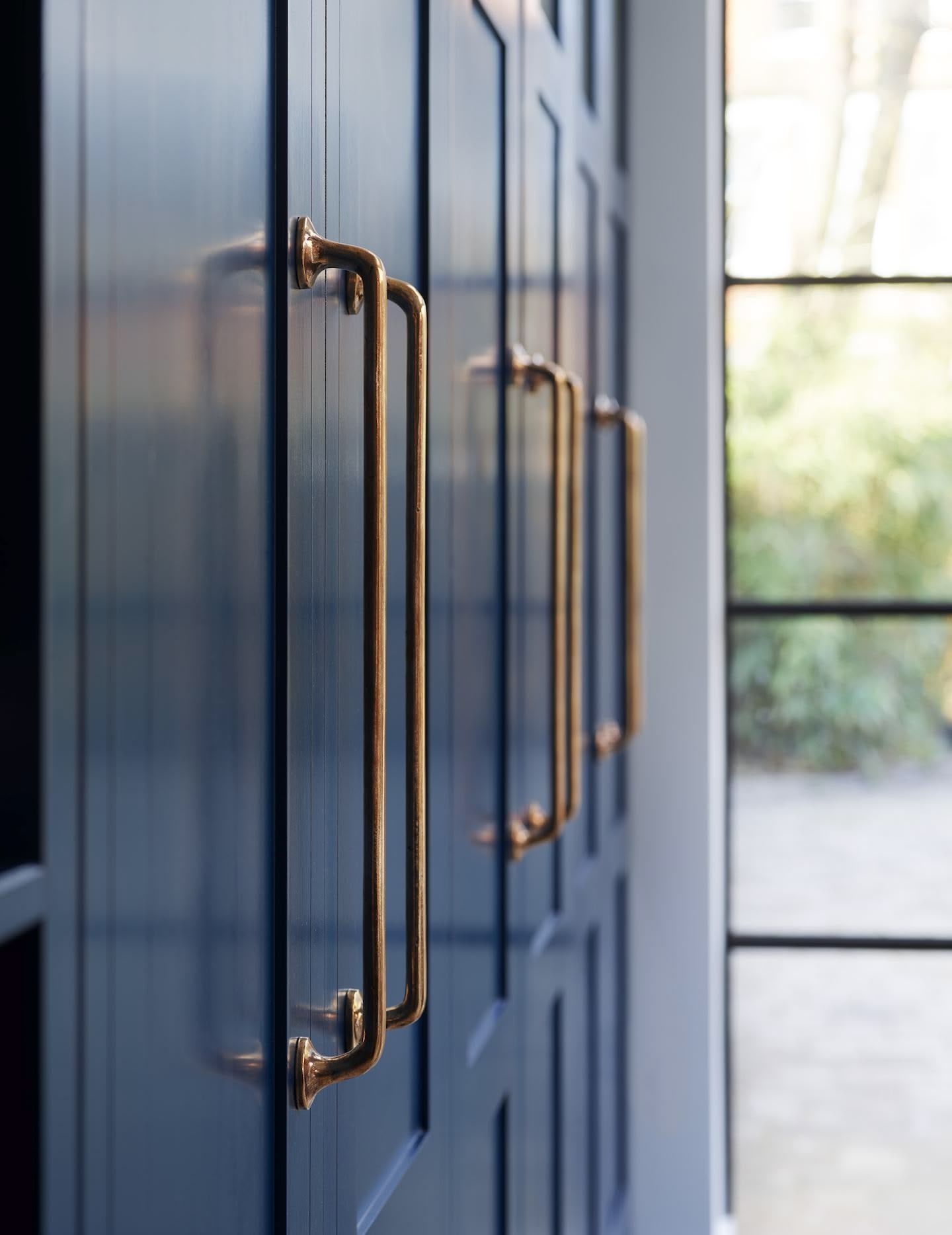 Closeup of navy Shaker kitchen cabinetry with industrial style brass handles