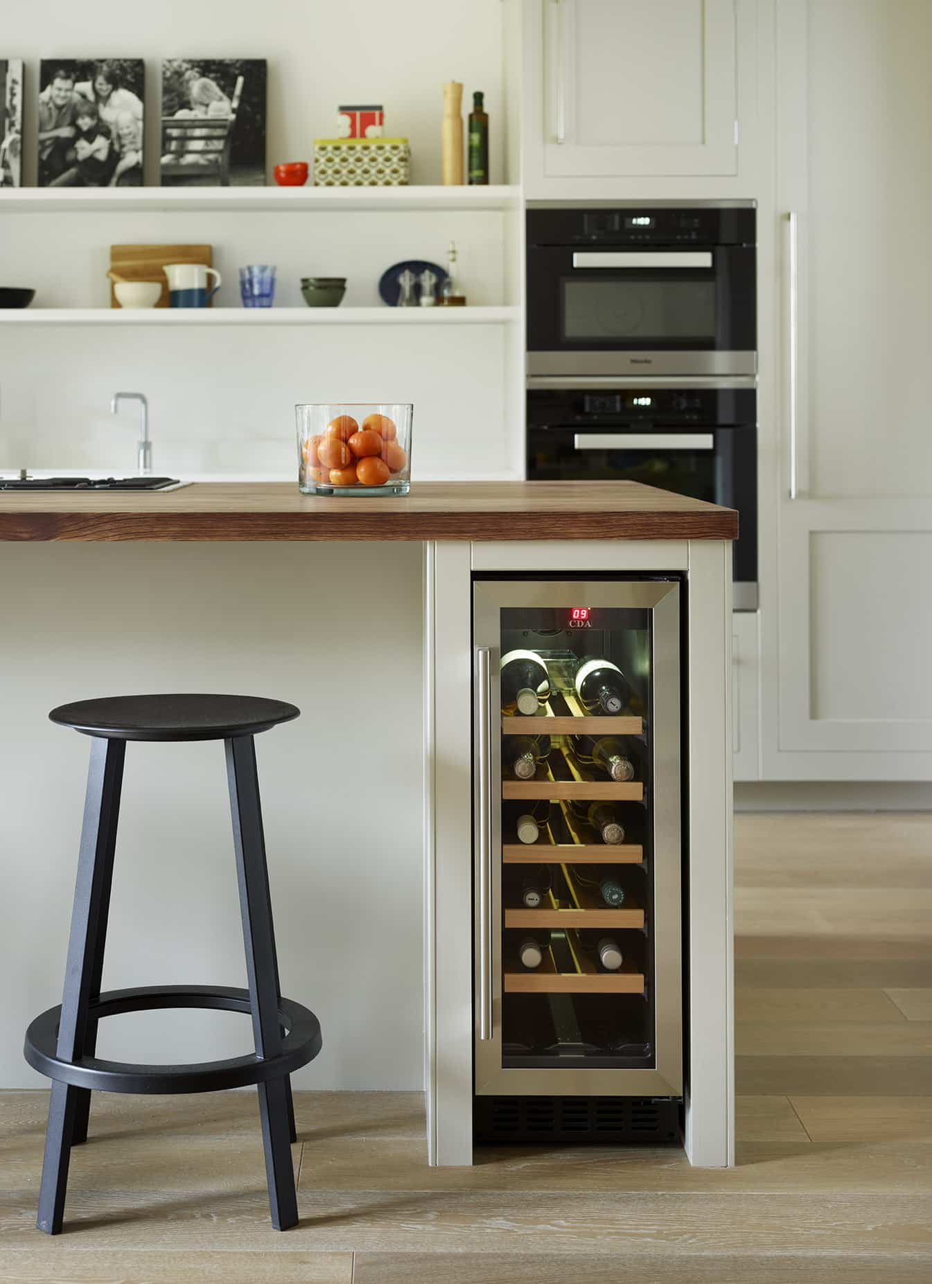 White Shaker kitchen island with walnut worktop featuring black bar stool and wine fridge