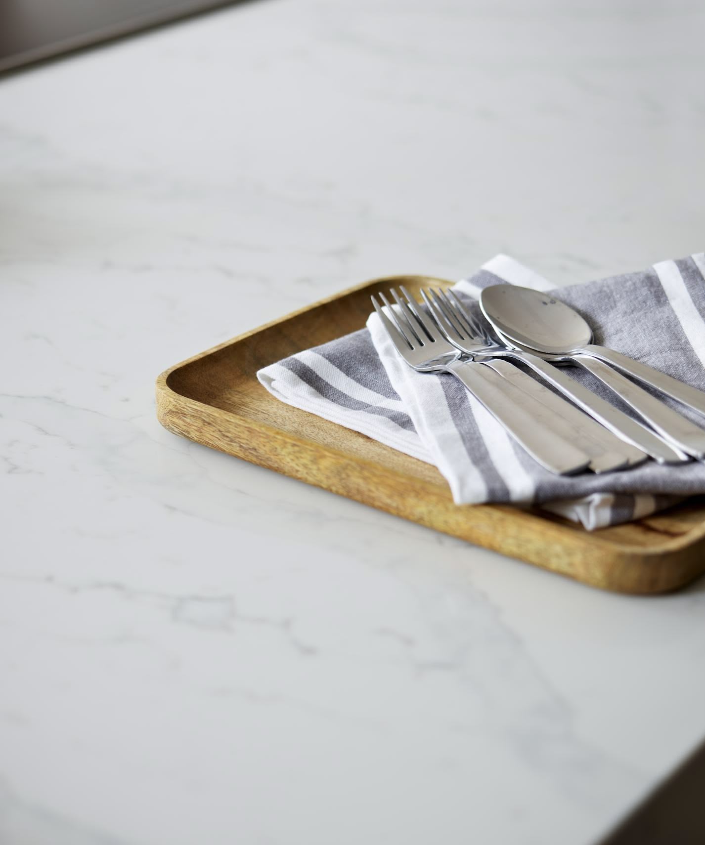 Close up of white marble worktop with cutlery on a chopping board