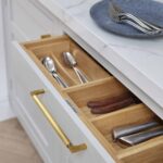 Light grey kitchen drawer with oak interior open to show organised cutlery storage