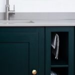Rich green Shaker kitchen cabinetry with grey worktop and silver tap