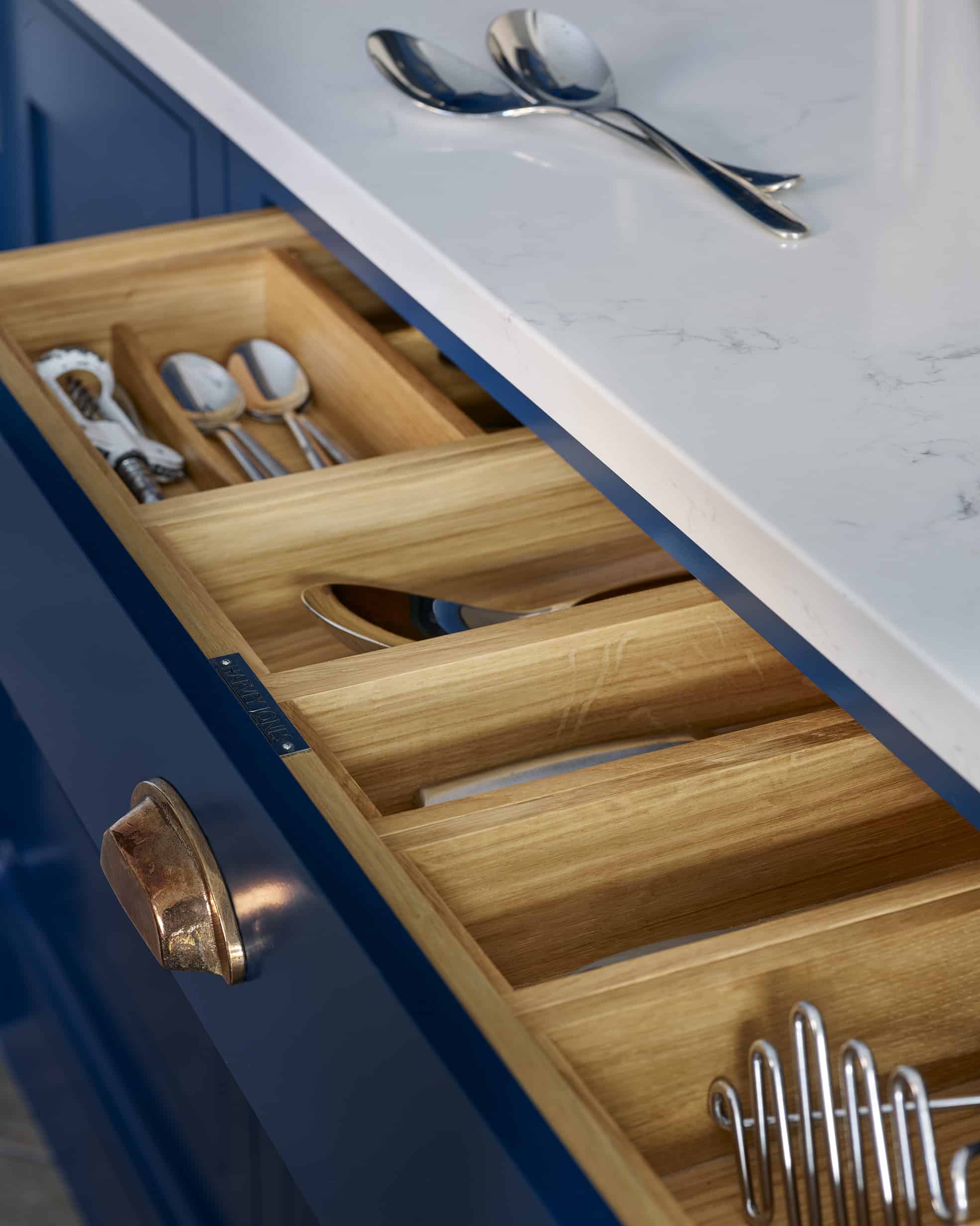 Closeup of navy Shaker kitchen drawer open to show light oak interior