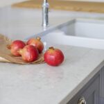 Closeup of white basin sink with silver tap next to grey marble worktop