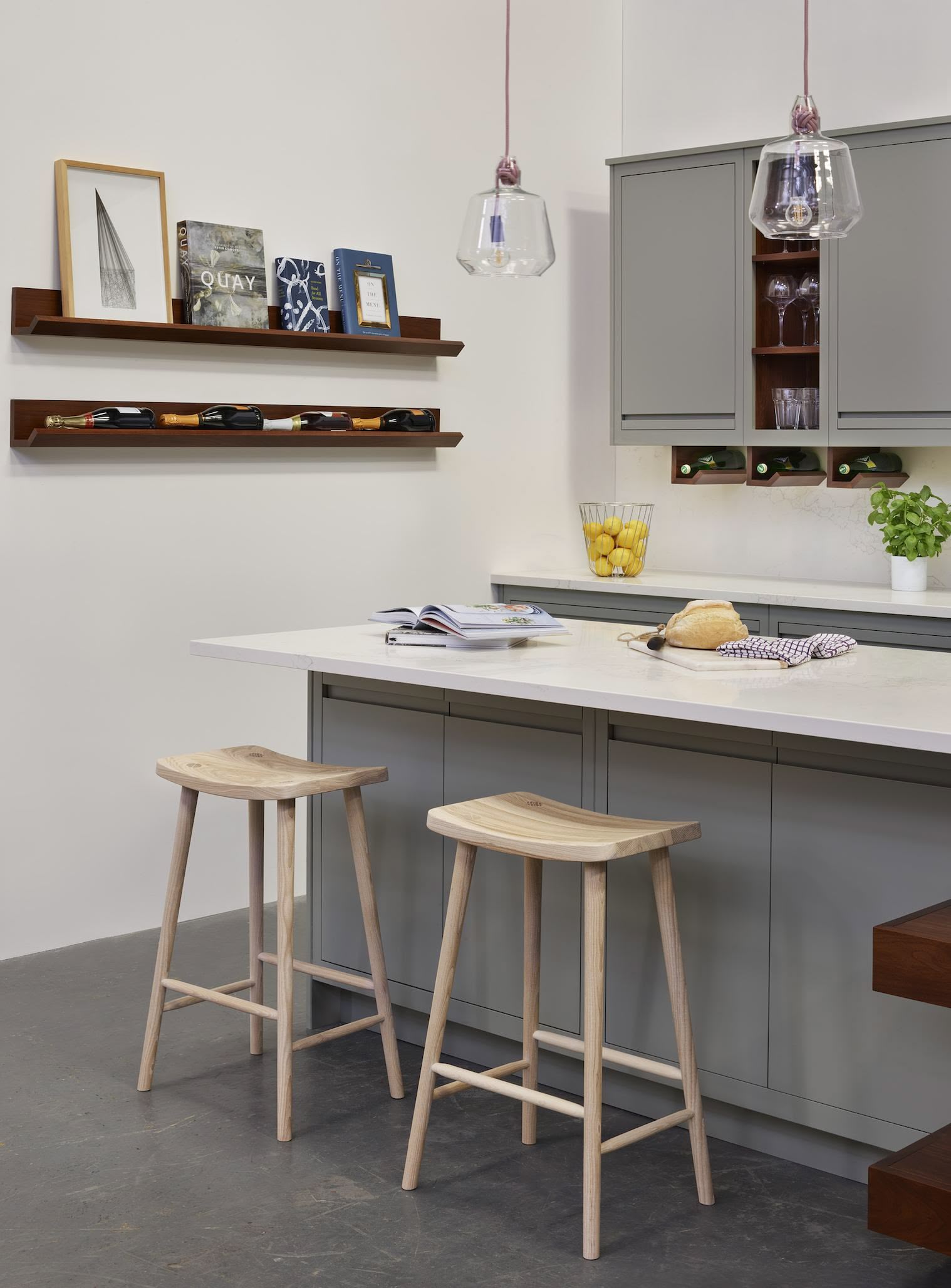 Green-grey kitchen island with white worktop featuring natural wood smile stools