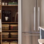 Open pantry next to American style fridge showing organised storage shelving