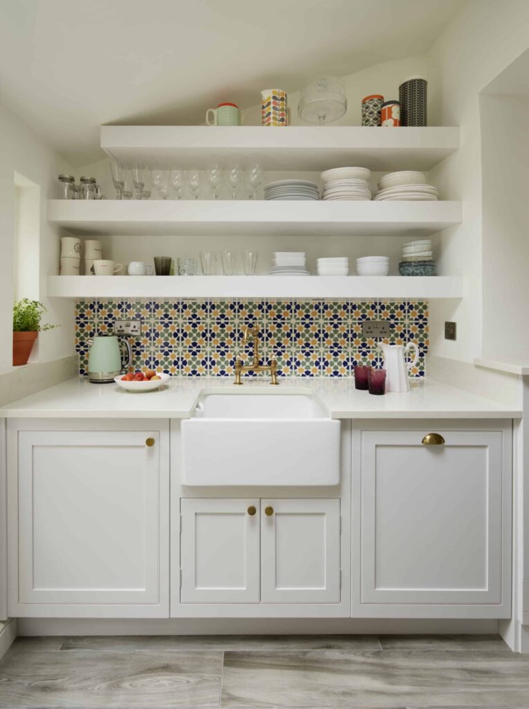 Arbor kitchen cabinetry in a small galley kitchen with open shelving, moroccan style tiles and brass hardware