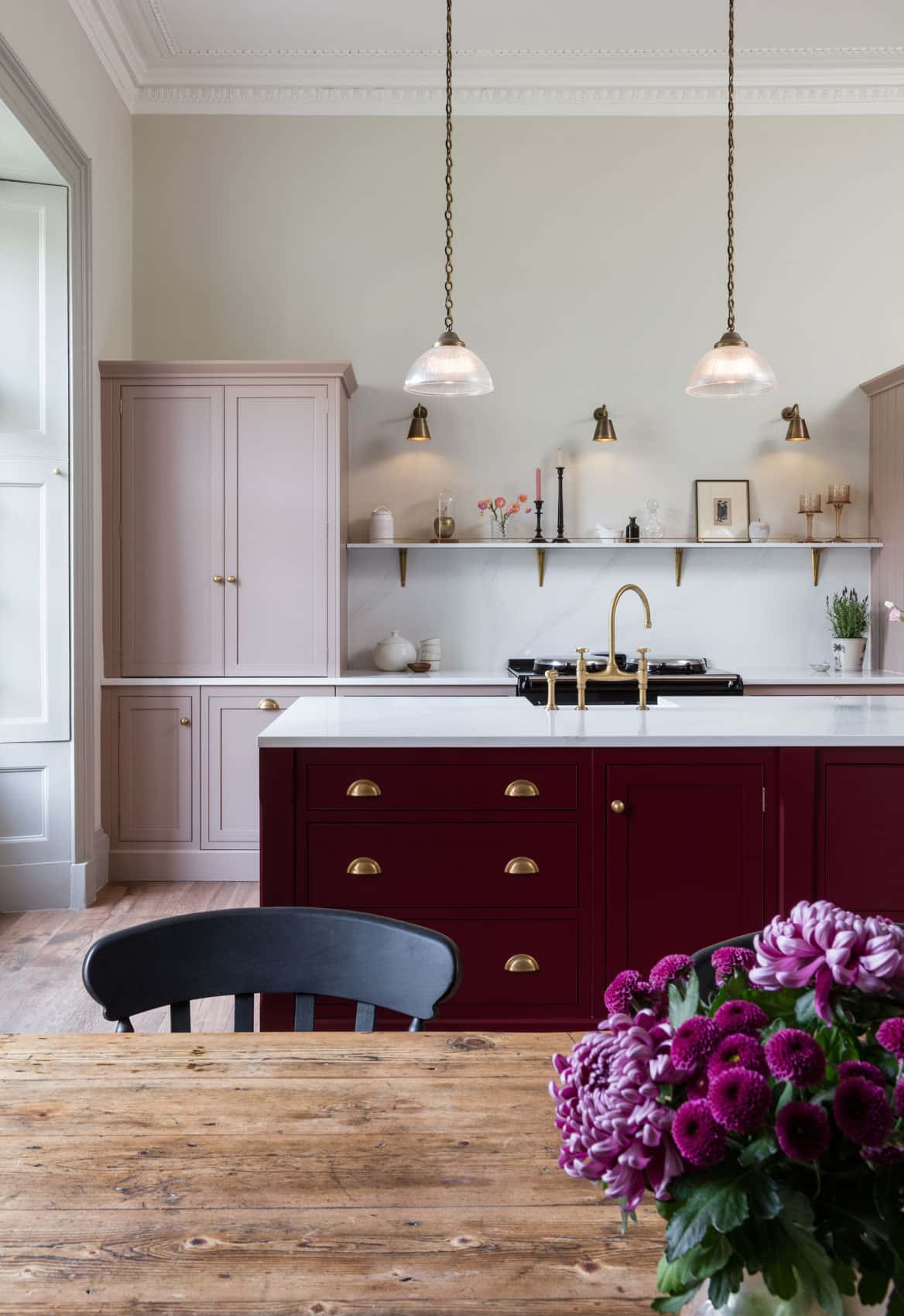 Burgundy kitchen island with brass drawer handles and white worktop