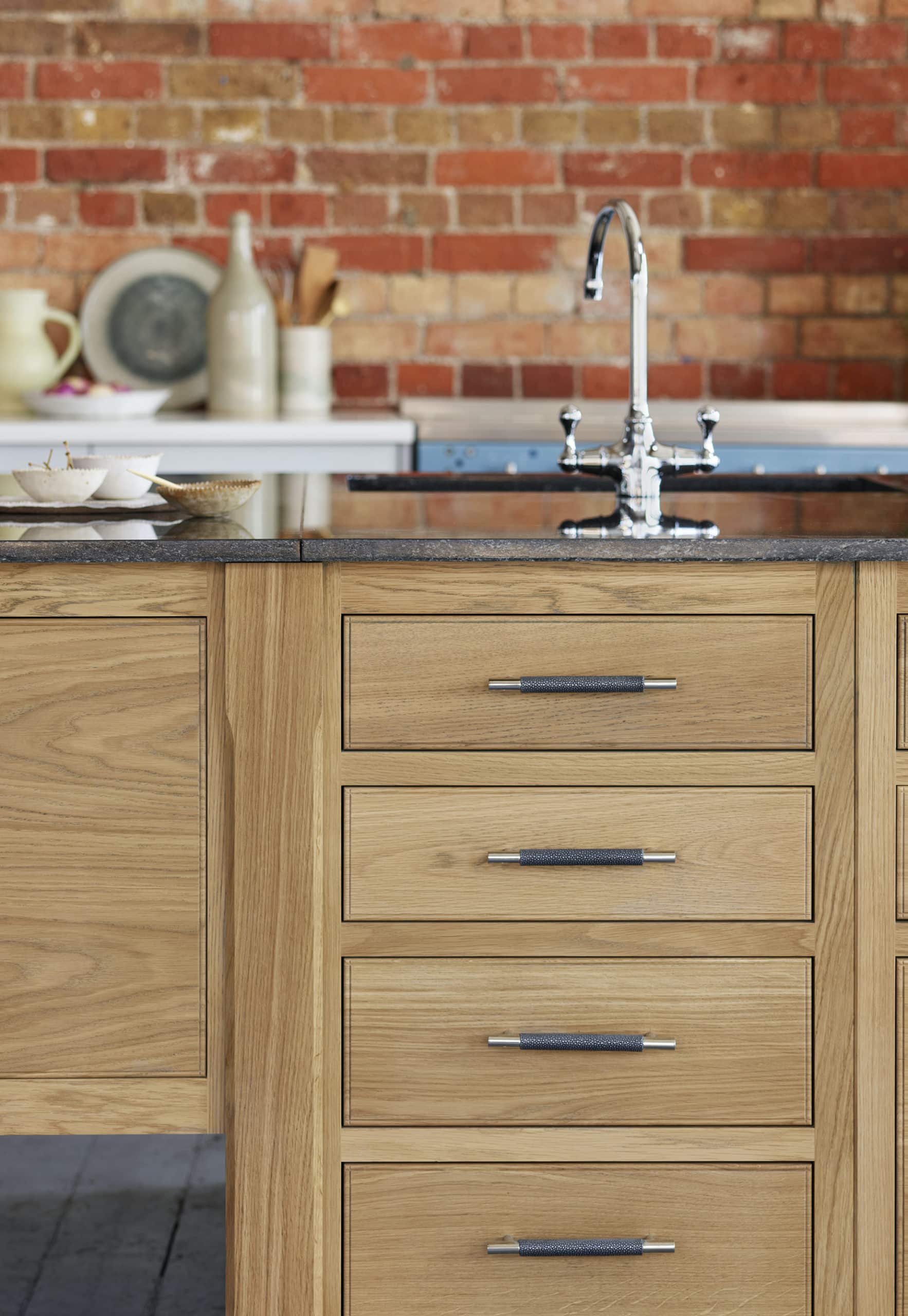 Oak kitchen island with black worktop with black sink and silver tap