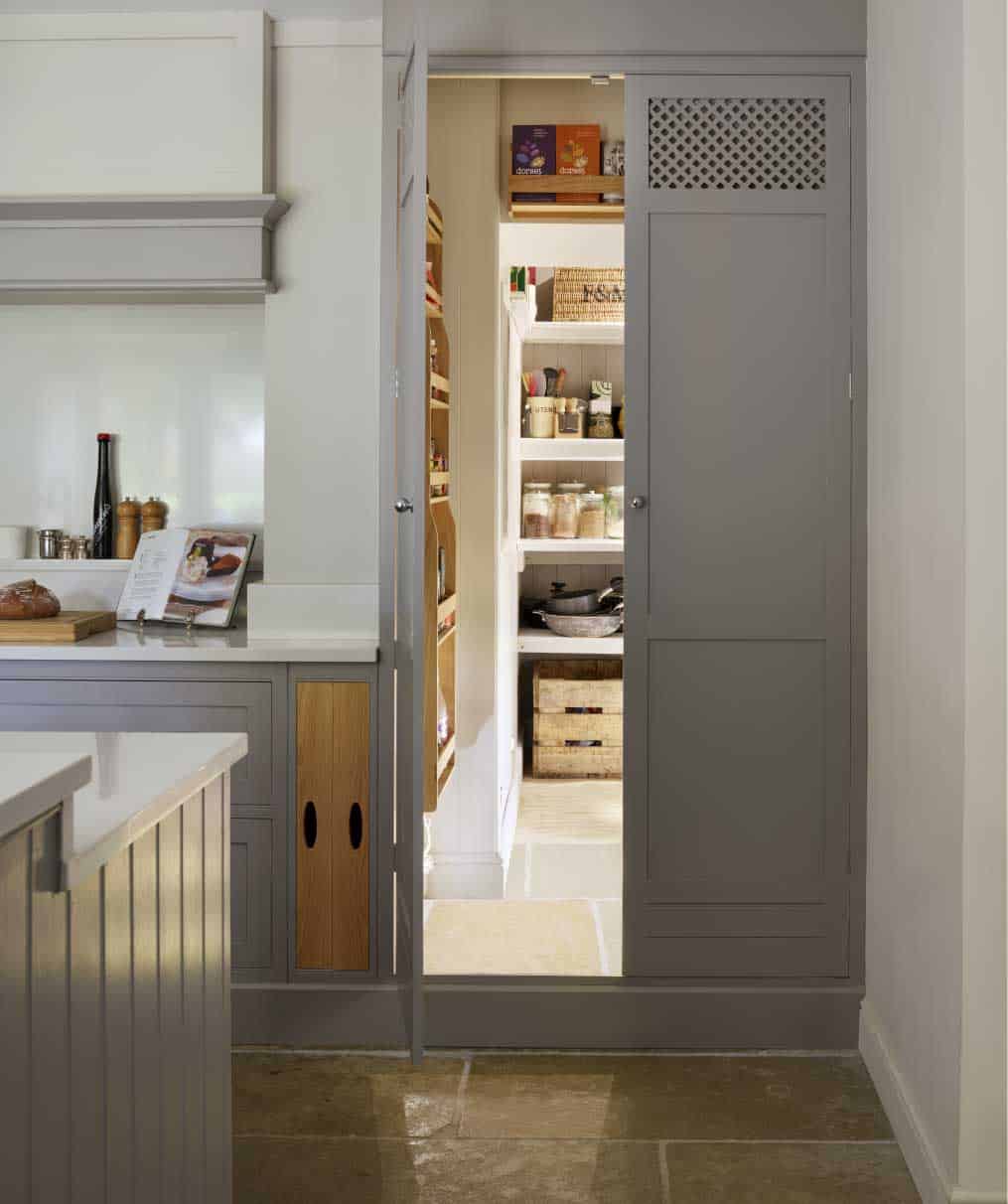 Grey kitchen doors open to show hidden walk-in kitchen pantry
