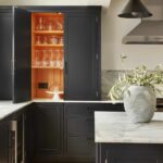 Dark Arbor kitchen cabinetry open to reveal orange lining and glassware storage