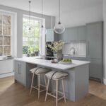 Green-grey Linear style kitchen island with white worktop featuring wooden stools