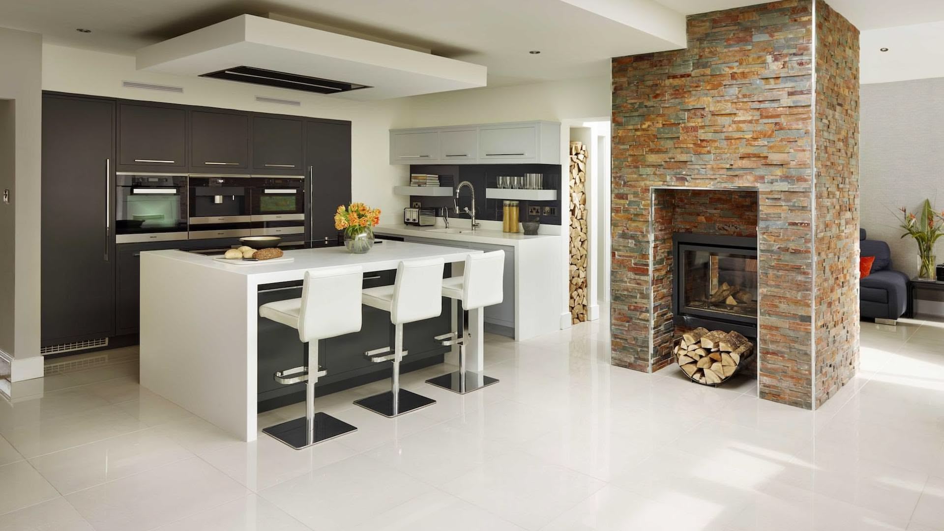 Grey and white two-tone Linear kitchen design featuring natural brick fireplace