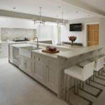 White kitchen island with integrated sink and breakfast bar with white stools