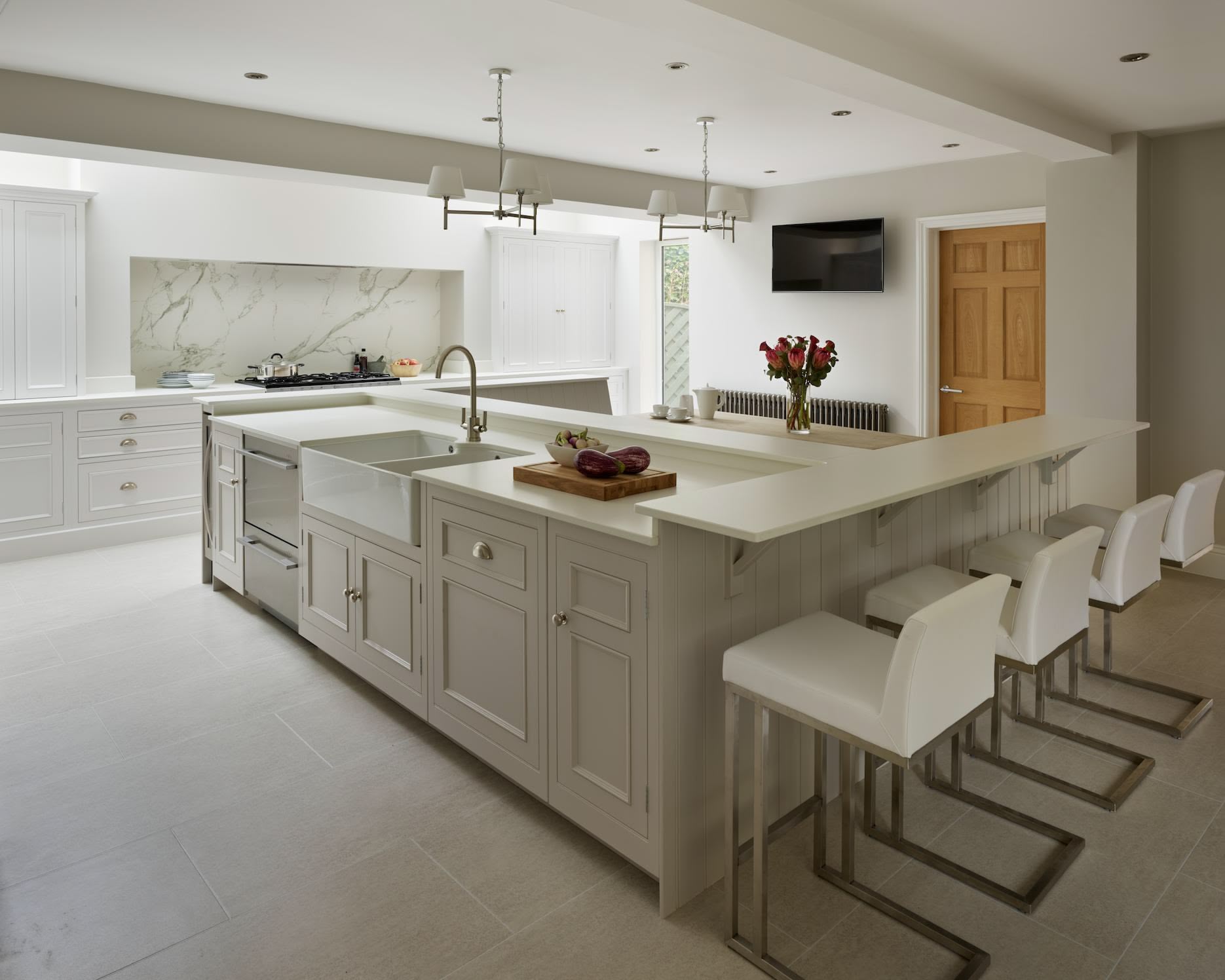 White kitchen island with integrated sink and breakfast bar with white stools