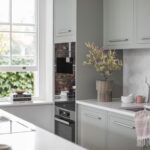 Green-grey Linear kitchen cabinetry with white worktops and silver handles