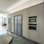 Grey Linear kitchen cabinetry featuring integrated oven and American fridge