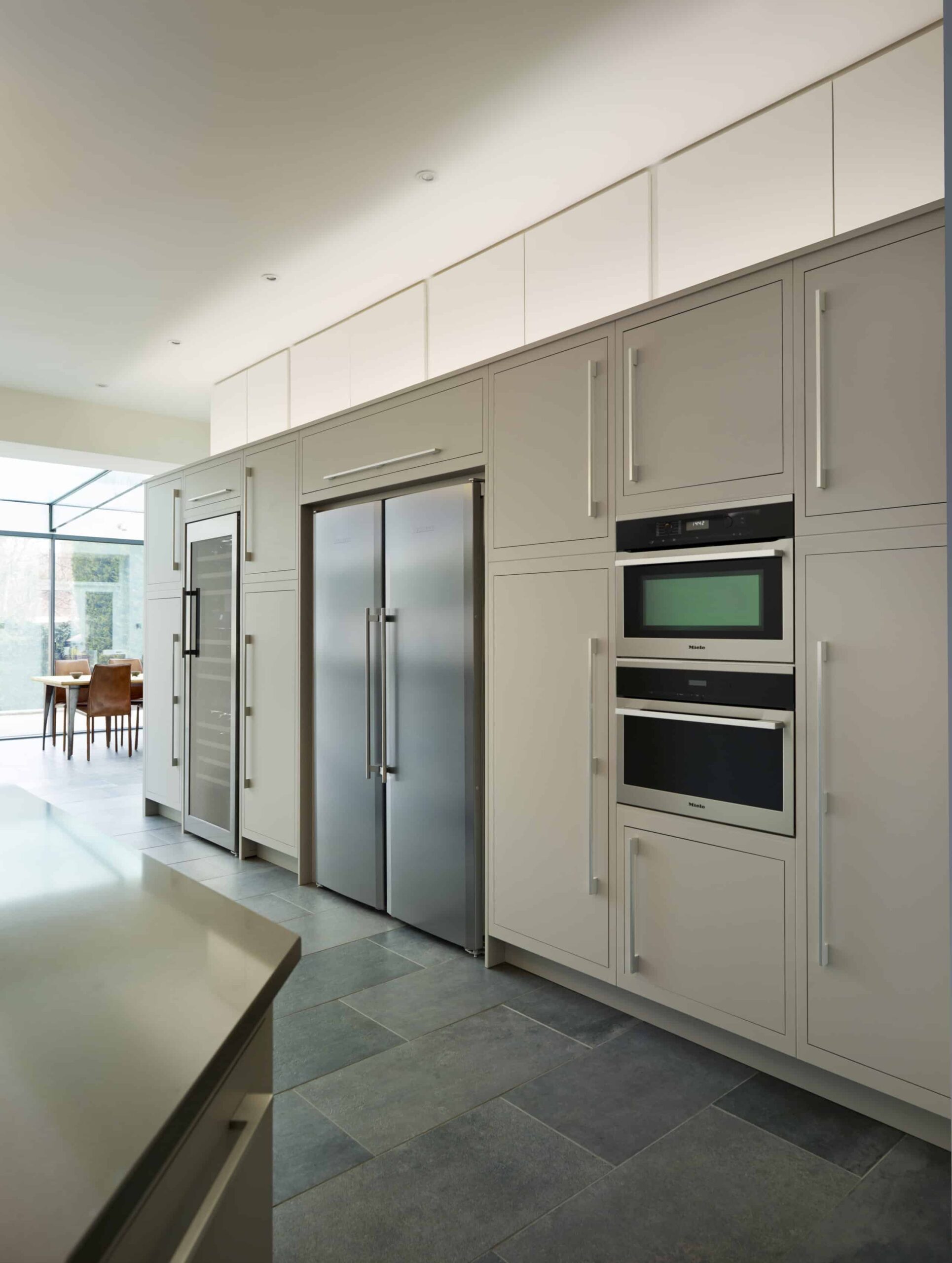 Grey Linear kitchen cabinetry featuring integrated oven and American fridge