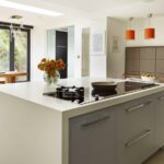 Kitchen island featuring grey cabinetry and white worktop with integrated hob