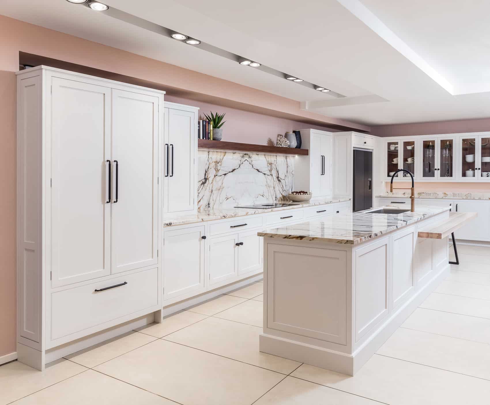 White Arbor kitchen cabinetry with white and pink marble worktops against pale pink walls