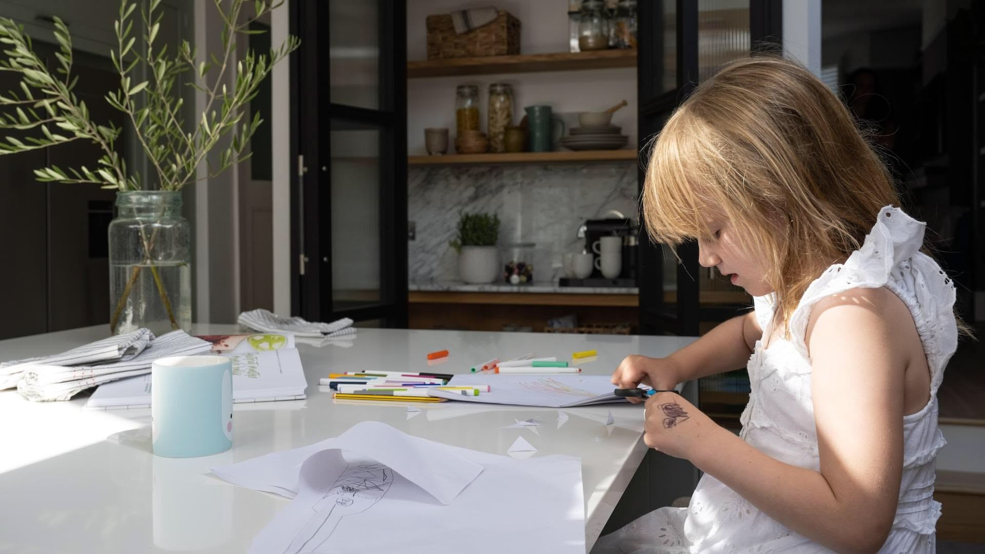 Young child drawing sat at a kitchen island with white worktop