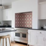 White Shaker kitchen cabinetry with dark worktops and decorative tiled cooker alcove