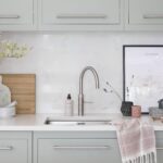 Green-grey Linear kitchen sink area featuring green-grey cabinetry and white worktops with silver sink and tap