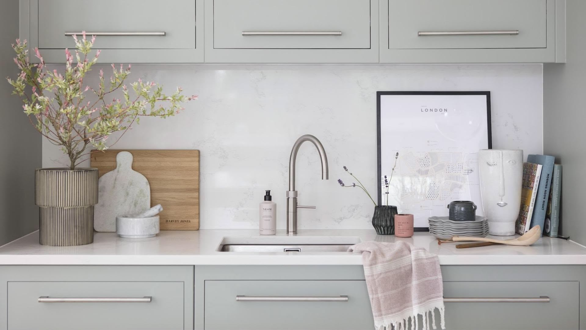 Green-grey Linear kitchen sink area featuring green-grey cabinetry and white worktops with silver sink and tap