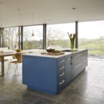 Blue kitchen island with Linear cabinetry and white worktop with integrated hob