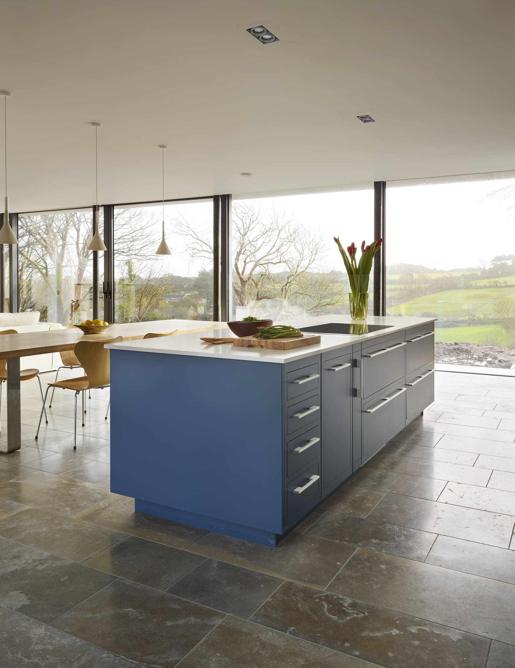 Blue kitchen island with Linear cabinetry and white worktop with integrated hob