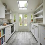 White Shaker kitchen cabinetry with cream worktops and decorative tiled cooker splashback
