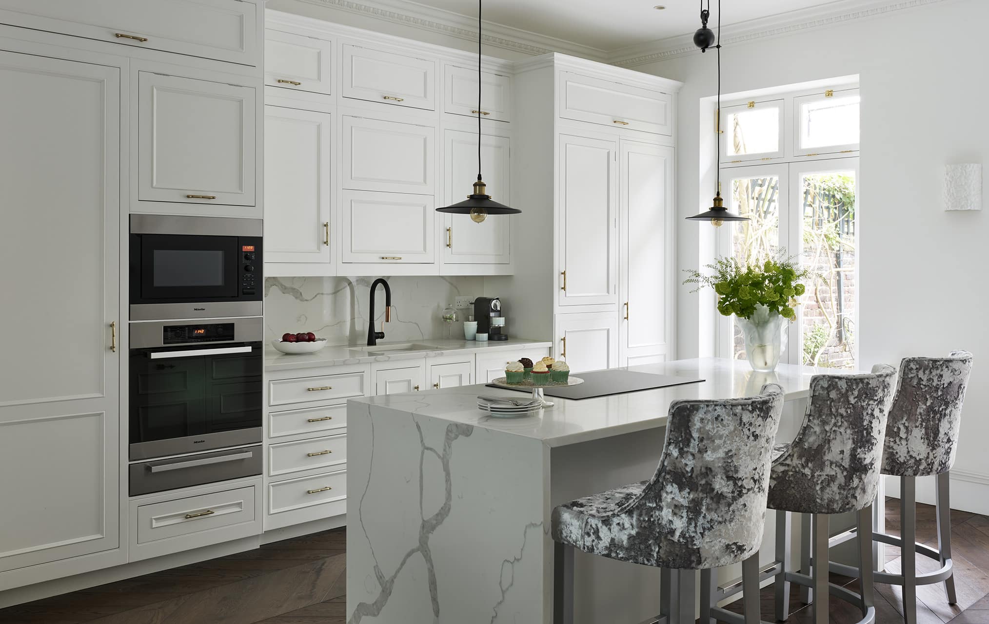 Bright white Shaker kitchen cabinetry with marble kitchen island worktop and waterfall edge