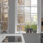Kitchen island with white worktop and integrated hob next to a white paned window