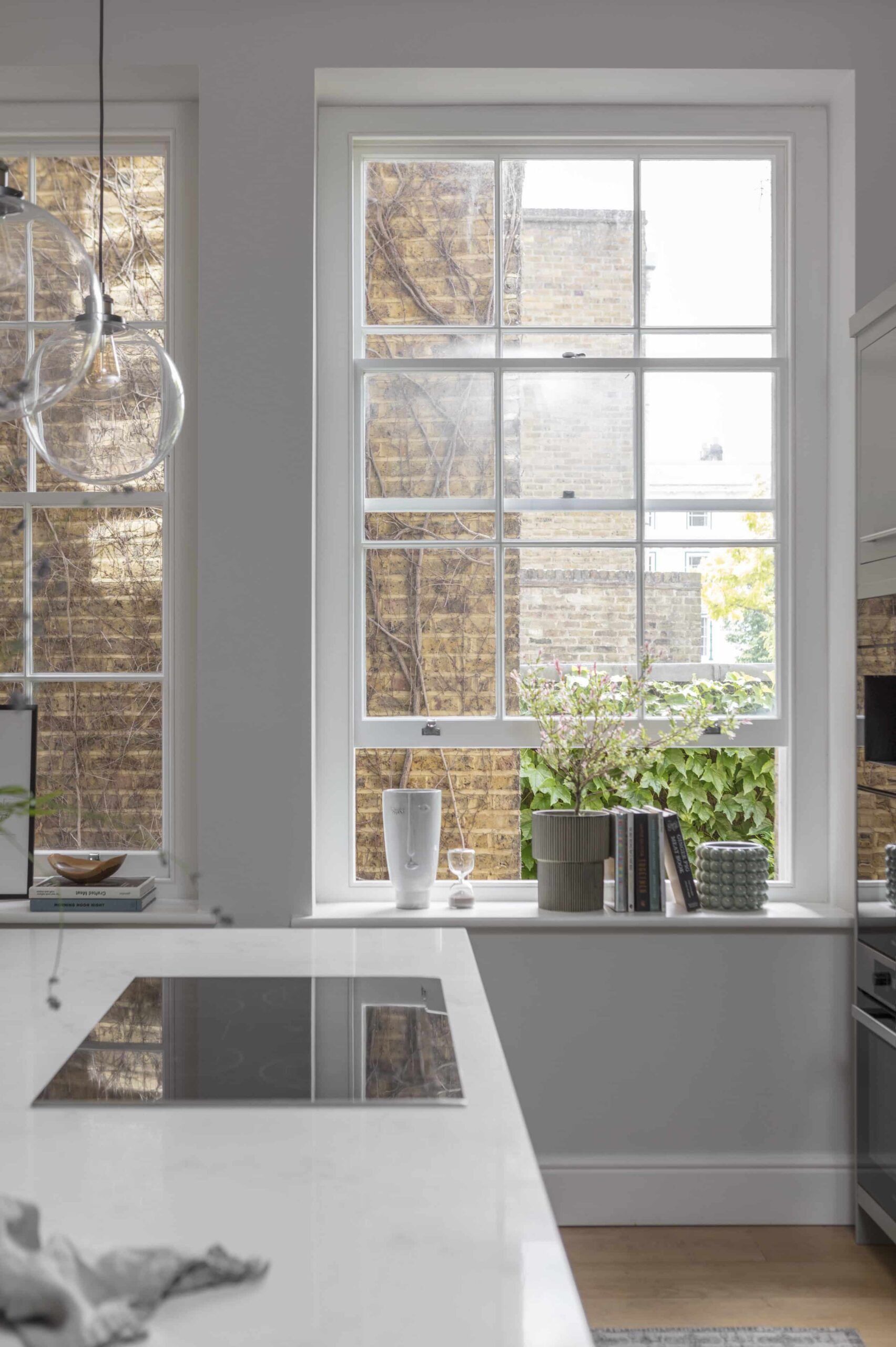 Kitchen island with white worktop and integrated hob next to a white paned window