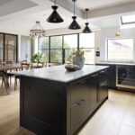 Dark Arbor kitchen island featuring white marble worktop in front of a kitchen dining area
