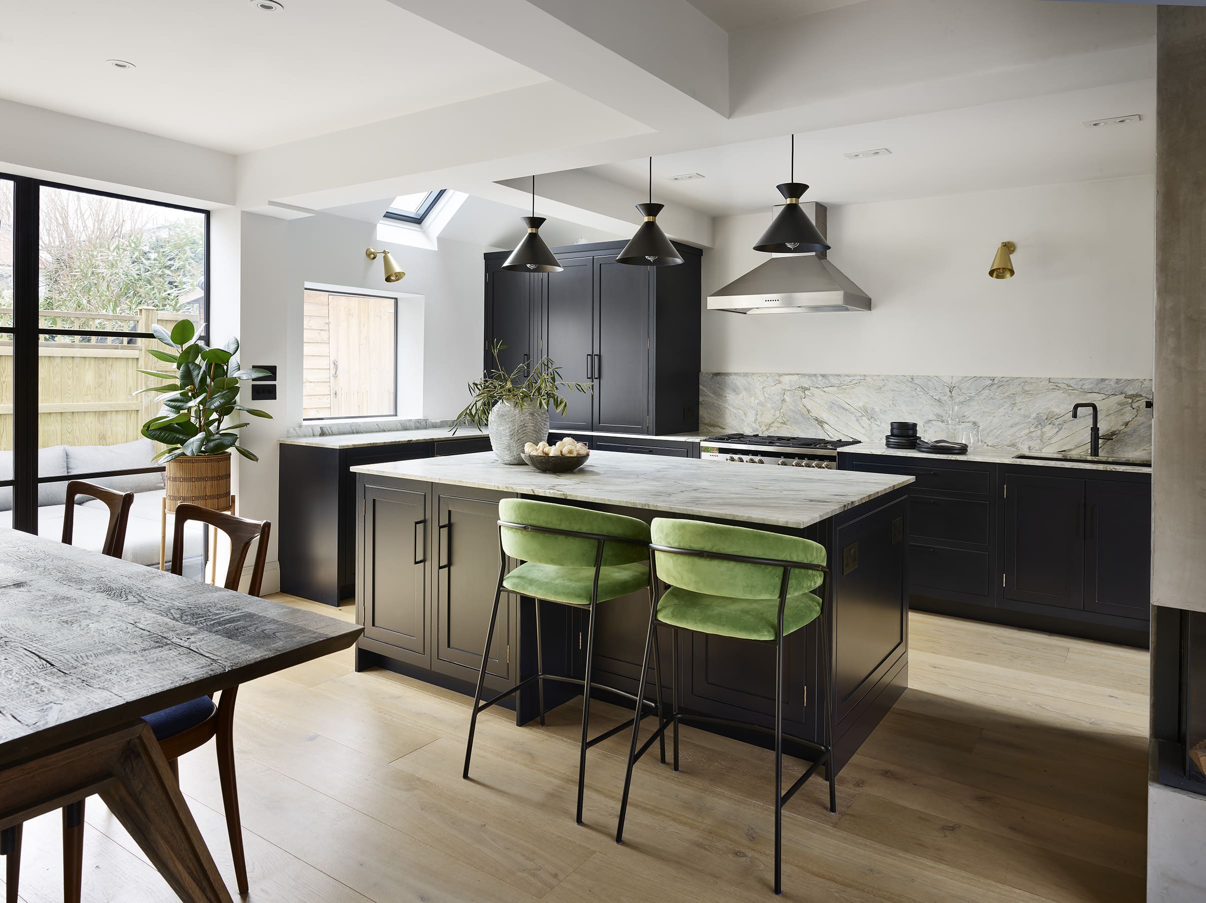 Dark Arbor kitchen island with white marble worktop featuring green stools