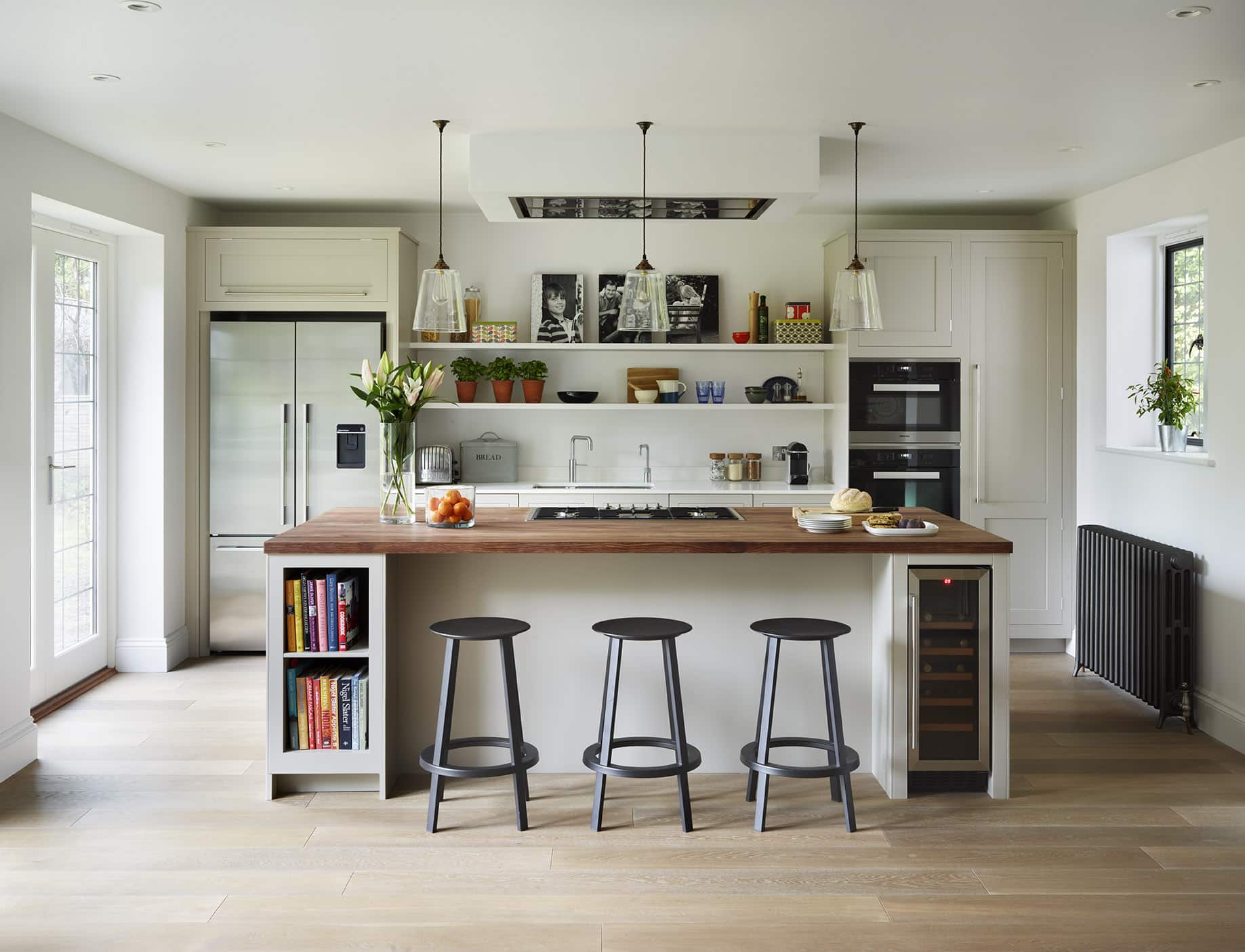 White Shaker kitchen cabinetry with white kitchen island featuring walnut worktop and wine fridge