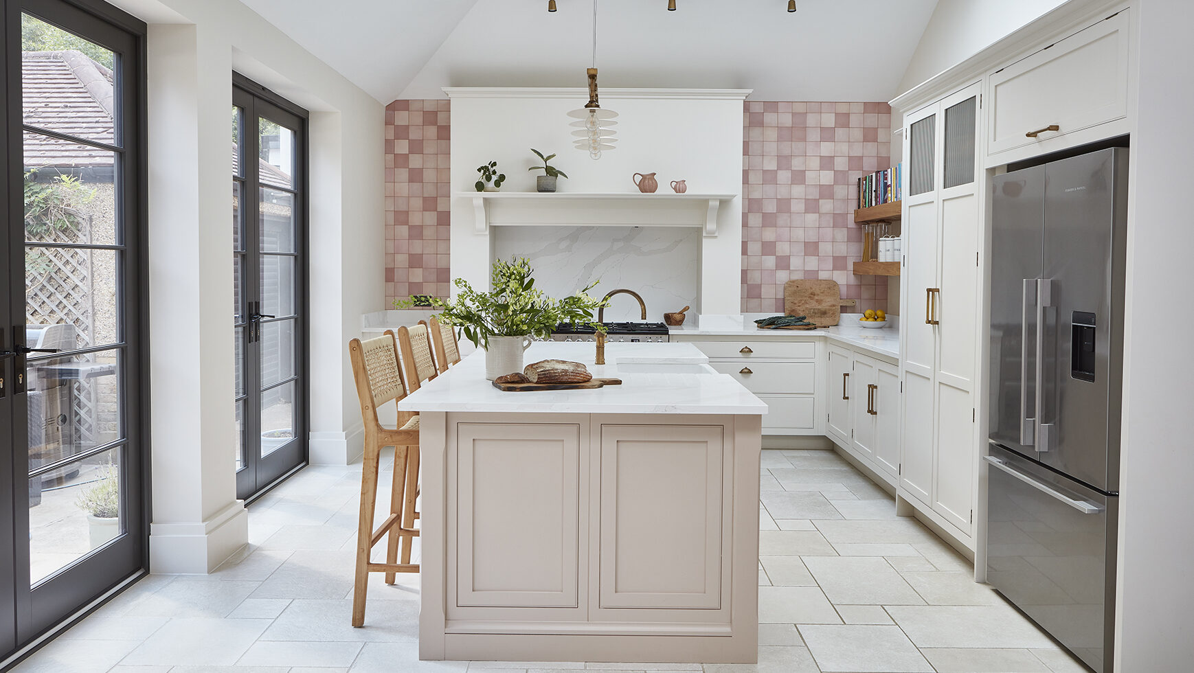 Bespoke kitchen island with seating and sink in pink kitchen with natural light