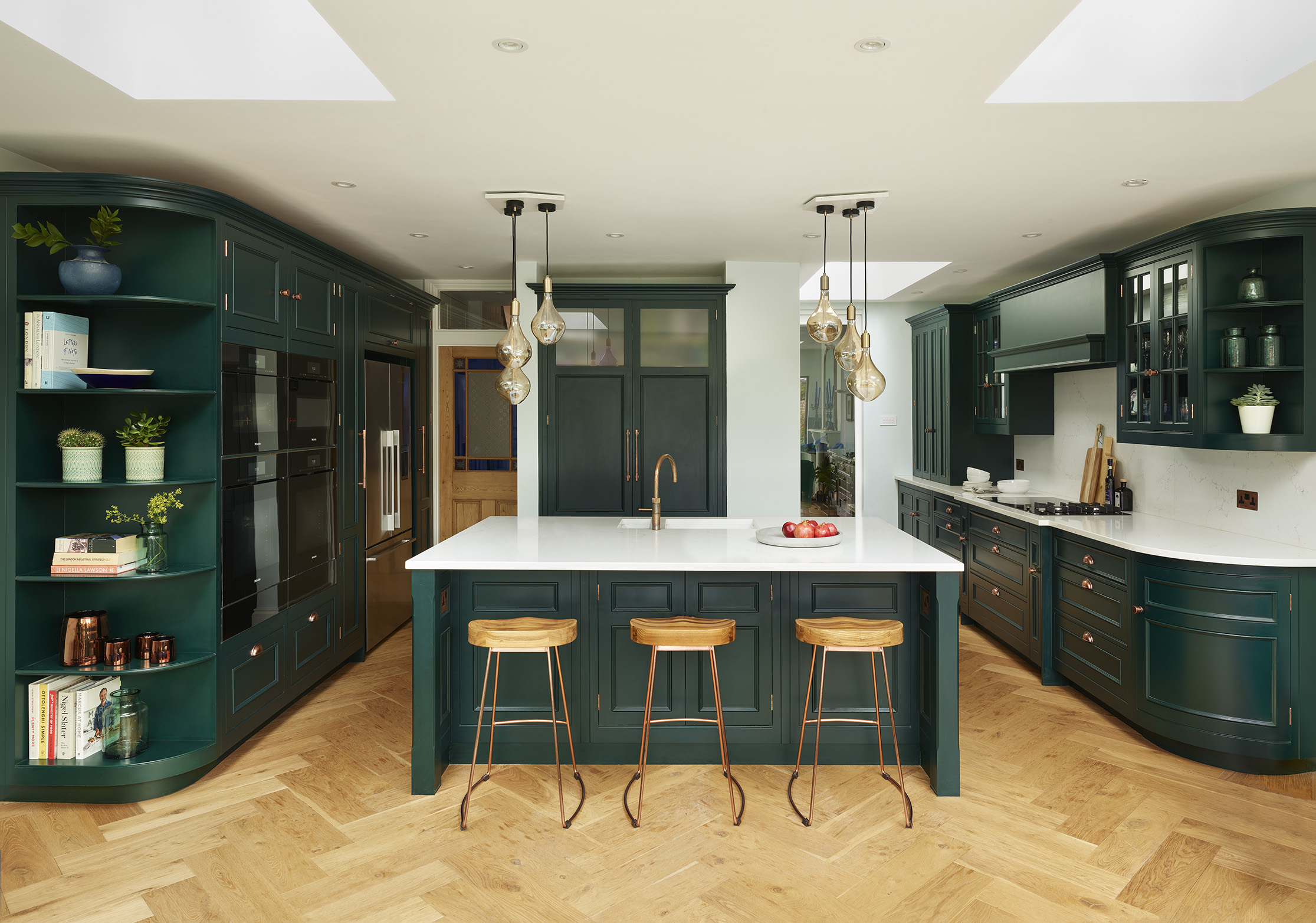 Forest green kitchen with quartz worktops and a kitchen island with a sink