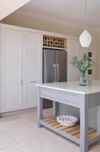 Grey kitchen island with white worktop featuring drawers and open shelving