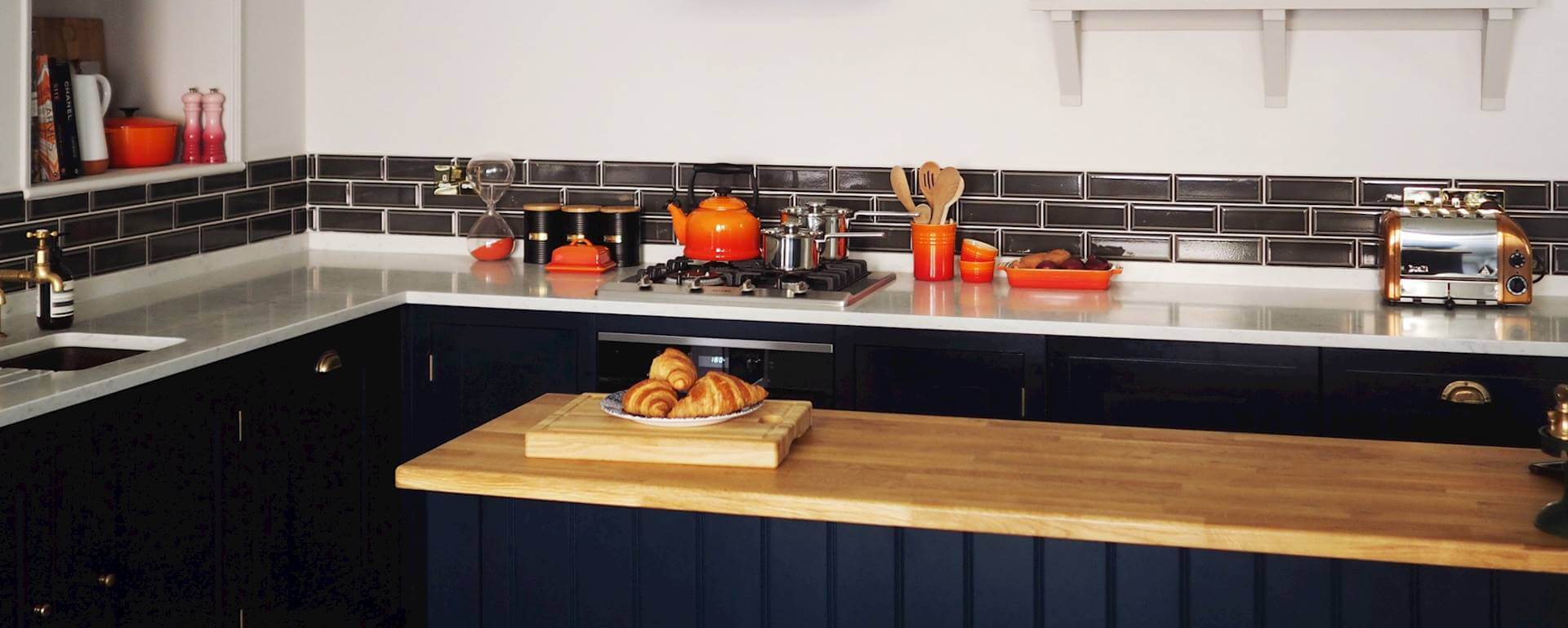 Dark cabinetry with white marble worktop and dark kitchen island with oak worktop