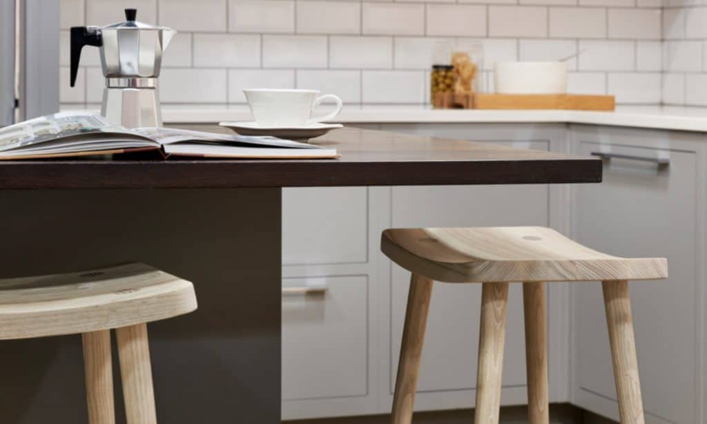 modern kitchen island with dark wood worktop and natural wood smile stools
